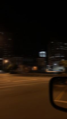 a blurry photo of a city street at night with buildings in the back ground