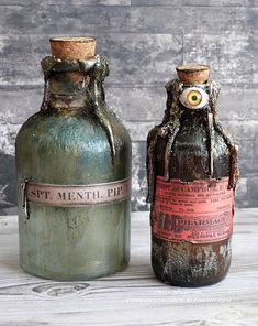 two old fashioned bottles sitting next to each other on a wooden table with peeling paint