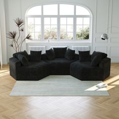 a large black couch sitting on top of a hard wood floor next to a window