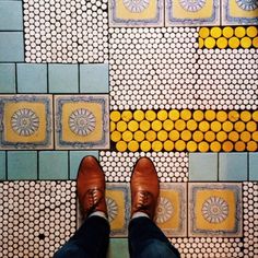 a person standing on top of a tiled floor next to yellow and blue tile tiles