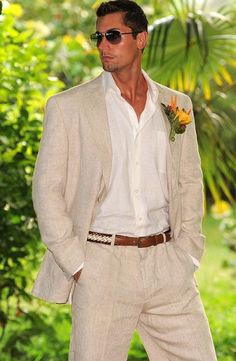 a man in a white suit and flower boutonniere is posing for the camera