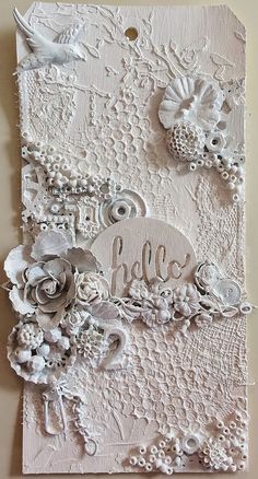 an art work made out of paper with flowers and lace on the bottom, which reads hello