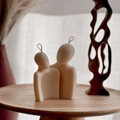 two small figurines sitting on top of a wooden table next to a window