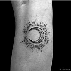 a black and white photo of a sun and moon tattoo on the left calf leg