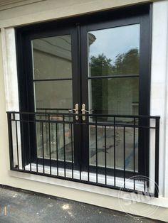 an open window on the side of a building with black iron railings and glass doors