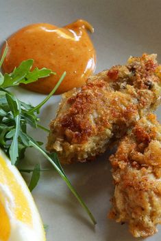 some fried food is sitting on a plate next to an orange and ketchup