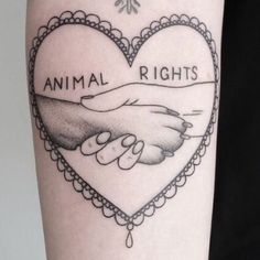 a tattoo on the arm of a woman with an animal rights heart and two hands holding each other