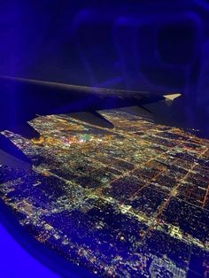 an aerial view of the city lights at night as seen from inside an airplane window