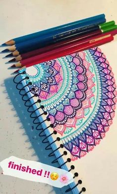 some pencils are laying on top of a spiral notebook