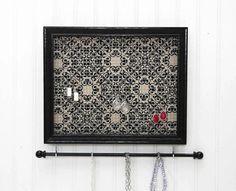 a black and white wall mounted jewelry rack with two necklaces hanging from it's sides