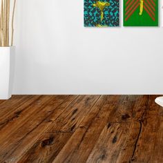 two paintings on the wall in a room with wood floors and white walls, one is green