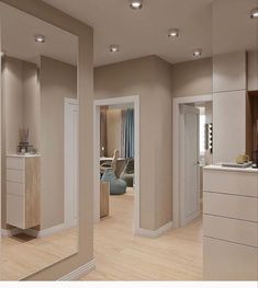 an empty living room and kitchen with large mirrors on the wall, in neutral colors