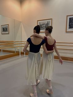 two ballerinas standing in front of a mirror with their backs to each other