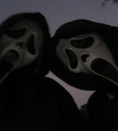 two people wearing masks in the dark with their faces covered by black and white cloths