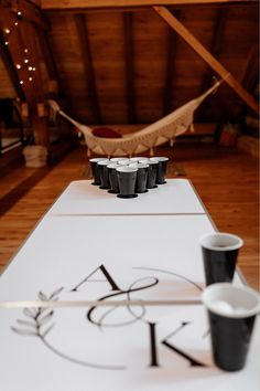 two cups are sitting on a table with a hammock in the back ground