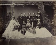 an old black and white photo of people dressed in formal wear posing for a family portrait