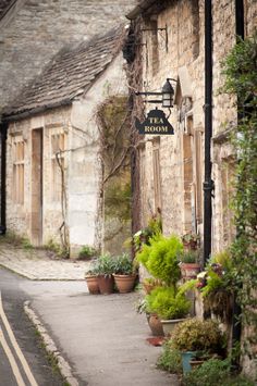 an old stone building with potted plants on the side and a sign that says tea room