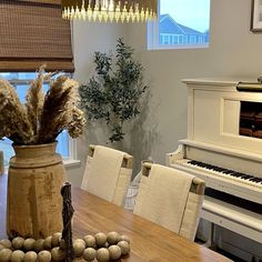 a wooden table topped with a vase filled with flowers next to a piano and window