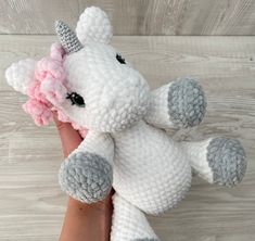 a crocheted stuffed unicorn with a pink flower