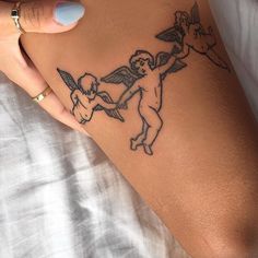 a woman's arm with an angel tattoo on it and two cherubs