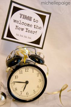 an alarm clock sitting on top of a table next to a sign that says time to welcome the new year