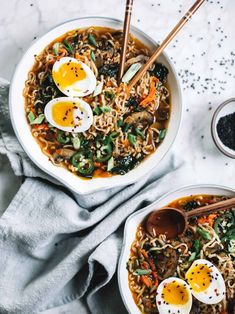 two bowls of ramen with eggs on top and chopsticks in the bowl