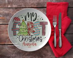 a white plate with a christmas design on it next to a fork and knife, along with a red napkin