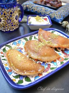 some pancakes are on a colorful plate with gold flecks and blue vases in the background