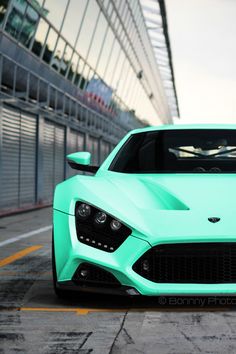 a blue sports car parked in front of a building