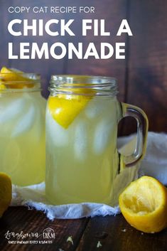 two mason jars filled with lemonade sitting on top of a table next to sliced lemons