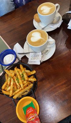 two cups of coffee and some french fries on a table