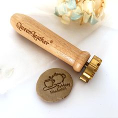 a wooden rolling pin sitting on top of a table next to a bottle opener and flower