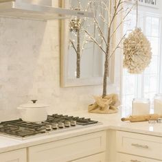 a kitchen with white cabinets and countertops has a tree in the middle of it