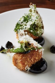 some sort of appetizer on a white plate with black olives and parmesan cheese