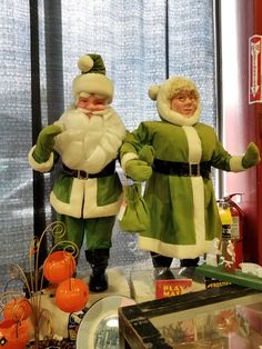 two statues of santa and mrs claus standing next to each other in front of a window