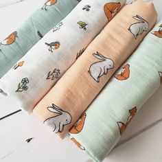 four baby swaddles in various colors and sizes with animals on them, sitting next to each other