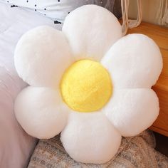 a white stuffed flower sitting on top of a bed