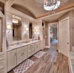 a large bathroom with wooden floors and chandelier above the sink, along with two walk in closets