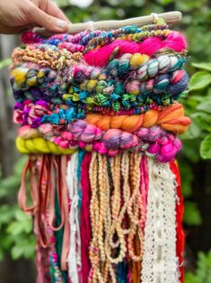 a person holding a bunch of colorful bracelets in front of some plants and trees