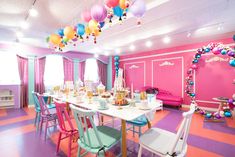 a dining room filled with lots of tables and colorful balloons hanging from the ceiling above it