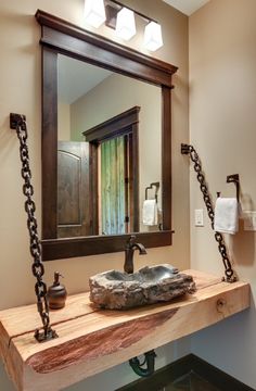 a bathroom sink sitting under a mirror next to a chain hanging on the wall above it