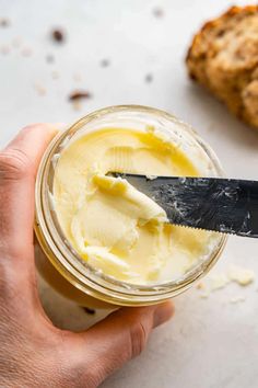 a person is holding a knife and spreading butter on top of cookie dough in a jar