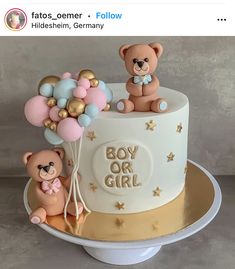 two teddy bears on top of a cake with gold and blue balloons in the shape of stars