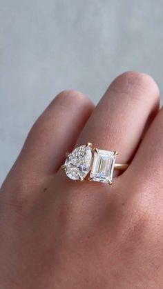 a woman's hand holding an engagement ring with two stones