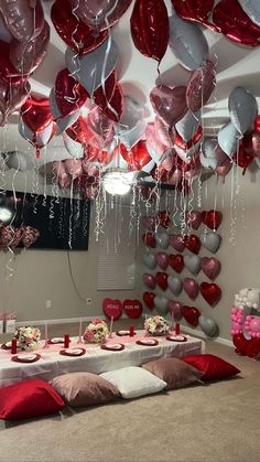 a room filled with lots of red and white balloons