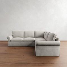 a large sectional couch sitting on top of a wooden floor next to a white wall