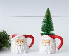 two mugs with santa claus faces and a christmas tree on the top are sitting next to each other