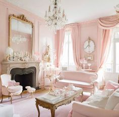 a living room filled with pink furniture and a chandelier hanging from the ceiling