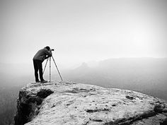 a man standing on top of a mountain while looking at the sky with a pair of skis