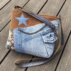 a denim purse with a star on the front and chain at the bottom, sitting on a wooden deck